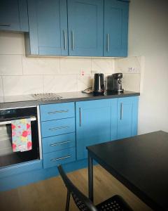 a kitchen with blue cabinets and a black table with a tableablish at Quiet Riverside Stopover by the Shannon in Leitrim +16 photos
