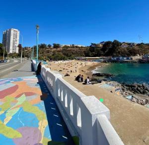 a beach with a bridge and people on the beach at Playa Las Torpederas in Valparaíso