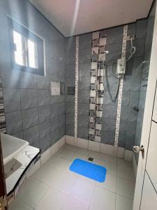 a bathroom with a shower and a blue mat on the floor at Placido's Vacation Home in Puerto Galera