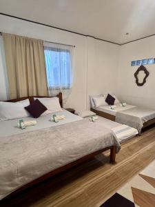 two beds in a hotel room with twothirdsessions at Placido's Vacation Home in Puerto Galera