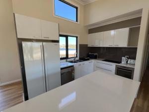 a kitchen with white cabinets and a refrigerator at Moore Memories Beach House in Guilderton