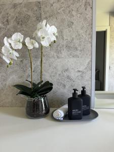 a bathroom counter with two bottles of soap and flowers at Portsea Paramount - When only the best will do in Portsea
