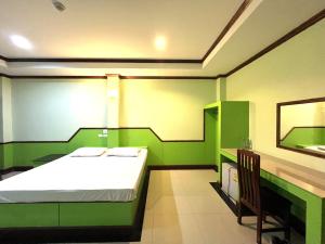 een groene slaapkamer met een bed en een spiegel bij Godkan Hotel in Ban Chuk Kum