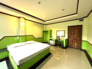 een groene slaapkamer met een bed en een tafel bij Godkan Hotel in Ban Chuk Kum