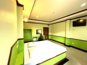 een slaapkamer met een wit bed en groene muren bij Godkan Hotel in Ban Chuk Kum