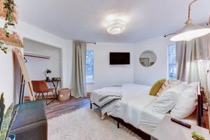 a white bedroom with a bed and a chair at Independence Bungalow in Wimberley