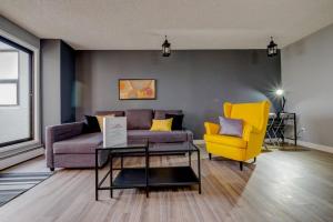 a living room with a couch and a yellow chair at Stylish DT Condo ~2 Blocks from Stampede Grounds in Calgary
