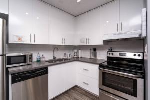 a kitchen with white cabinets and stainless steel appliances at Stylish DT Condo ~2 Blocks from Stampede Grounds in Calgary +19 photos