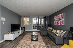 a living room with a couch and a tv at Stylish DT Condo ~2 Blocks from Stampede Grounds in Calgary