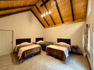 a group of four beds in a room with wooden ceilings at Bungalows Bosque Selah in Nebaj
