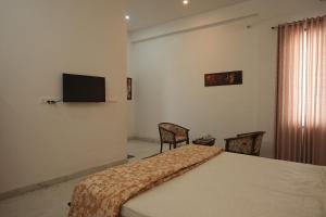 a bedroom with a bed with two chairs and a flat screen tv at Jagir villa in Udaipur