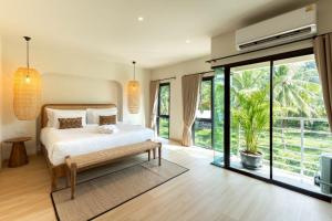 a bedroom with a bed and a large window at ELYSIUM Villa Khao Lak in Khao Lak
