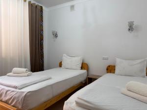 zwei Betten in einem Zimmer mit weißer Bettwäsche und Handtüchern in der Unterkunft Ulli Oy Boutique Hotel & Terrace in Xiva