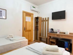 ein Zimmer mit zwei Betten und einem Fernseher an der Wand in der Unterkunft Ulli Oy Boutique Hotel & Terrace in Xiva