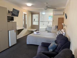 a room with a couch and a bed and a bathroom at Shady Rest Motel in Gympie