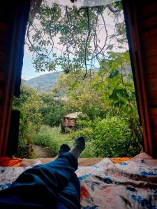 a man laying on a bed looking out a window at Tipi Miramelinda in Baños
