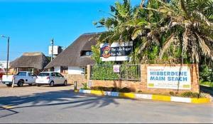 a parking lot with cars parked in front of a main beach at Angers Aweigh, Hibberdene Chalet 86 in Hibberdene
