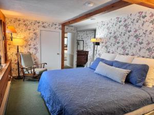 um quarto com uma cama azul e papel de parede floral em The Landgrove em North Landgrove