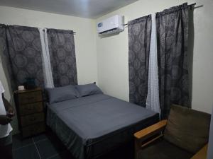 een kleine slaapkamer met een bed en een stoel bij Tiny Bliss Apartments in Potters Village