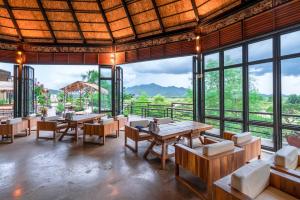 ein Restaurant mit Tischen und Stühlen und großen Fenstern in der Unterkunft Rai Ruen Rom Organic and Farmstay in Ban Sawan