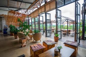 ein großer Raum mit Tischen und Stühlen und Fenstern in der Unterkunft Rai Ruen Rom Organic and Farmstay in Ban Sawan