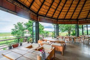 ein Restaurant mit Tischen und Stühlen und großen Fenstern in der Unterkunft Rai Ruen Rom Organic and Farmstay in Ban Sawan