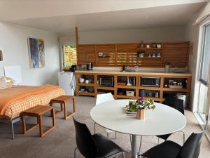 una stanza con un letto, un tavolo e delle sedie di Beach loft Makorori a Wainui