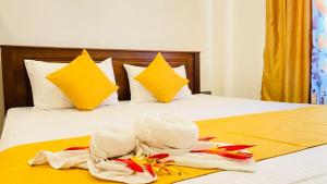 a bed with white towels and yellow and yellow pillows at Happy Haven in Hikkaduwa +9 photos