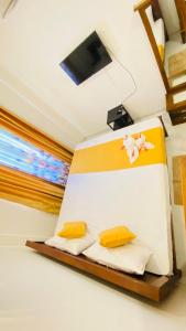 a room with a bed with yellow pillows and a tv at Happy Haven in Hikkaduwa
