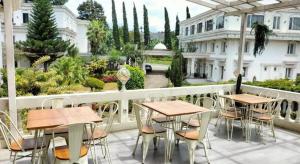 un patio avec tables et chaises sur un balcon dans l'établissement Rizen Premiere Hotel, à Puncak