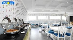 une salle à manger avec des tables et des chaises blanches et de la nourriture dans l'établissement Rizen Premiere Hotel, à Puncak