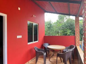 a patio with a table and chairs against a red wall at Malnad cloud homestay Agumbe in Someshwar