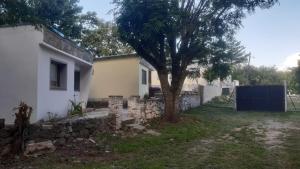 a house with a tree and a stone wall at Las Vertientes in Tanti +2 photos