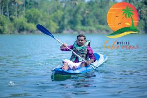 a man riding a paddle board on the water at Orchid Lake View Resort in Paravūr
