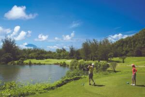 two people standing on a golf course next to a river at My Homestay in Tuaran