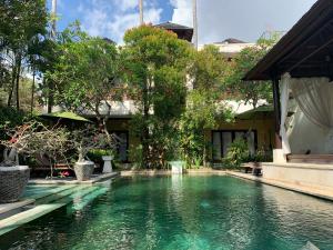 een zwembad voor een gebouw met bomen bij Nike Villas in Sanur