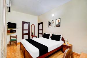 een slaapkamer met een groot bed en een stoel bij Townhouse Calangute Formerly Hotel Horizon in Goa