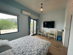 a bedroom with a bed and a flat screen tv at 出門獺踏 Otter footprints B&B in Jinsha