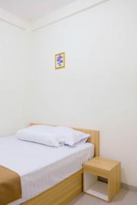 a bedroom with a white bed and a wooden table at Elmo Living in Yogyakarta +3 photos