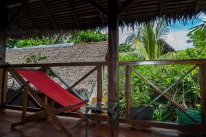 a hammock on the porch of a resort with a palm tree at Tiako Beach in Nosy Be
