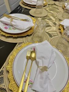 a table with white plates and gold forks and napkins at BLJ Homes in Angatan
