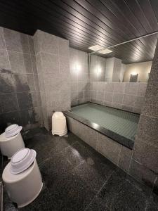 a bathroom with a bath tub with two toilets and a tub at Towa Ryokan in Kyoto
