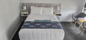 a bedroom with a bed with two tables and a chair at Albatross Motel in Lakes Entrance