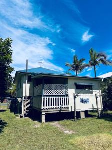 a small house with a blue roof and palm trees at Noosa River Gem in Noosaville +4 photos
