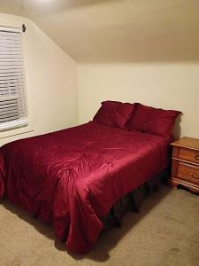 ein Schlafzimmer mit einem roten Bett und einem Nachttisch in der Unterkunft Historic Reno Home in Reno