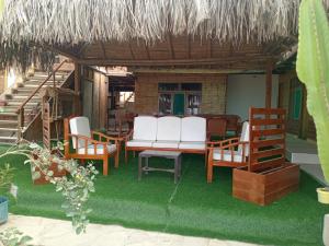 a patio with a table and chairs and a thatch roof at Black Marlin - Restaurant and Lodge in Talara