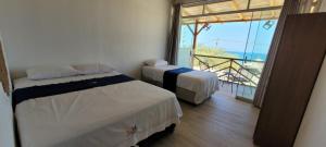 two beds in a room with a balcony at Black Marlin - Restaurant and Lodge in Talara
