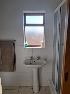 un bagno con lavandino e finestra di Coco 's Hamlet Flatlet a Prince Alfreds Hamlet