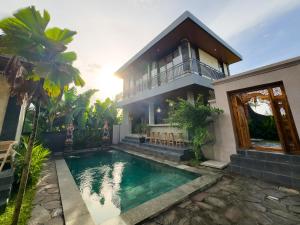 a house with a swimming pool in front of a house at Koeluma Bali in Ubud