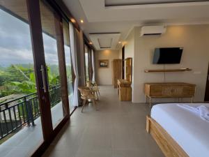 a bedroom with a balcony with a bed and a television at Koeluma Bali in Ubud